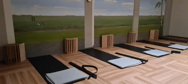 Lege zaal met matten, kussens, houten bankjes en riemen klaar voor een les; op de achterwand een landschapsschildering.